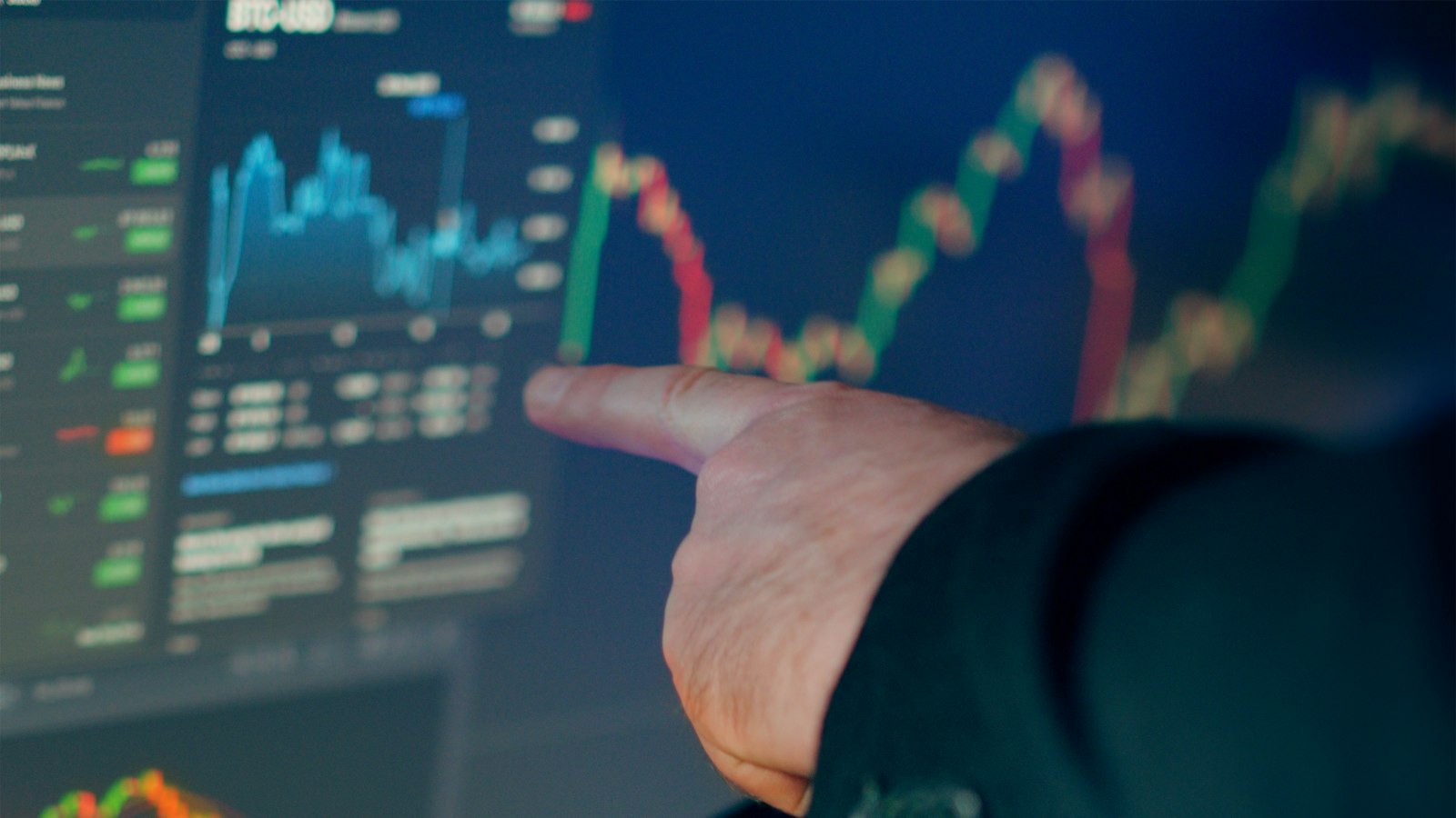 Trader analyzing stock market charts on multiple monitors